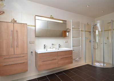 Das Vollbad mit Dusche, Eckbadewanne und Handtuchheizkörper.