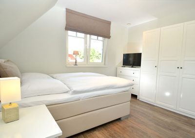 Schlafzimmer mit Flachbildschirm im Ferienhaus Strandreethus 2 in Lobbe
