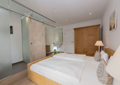 Schlafzimmer mit Doppelbett in der Ferienwohnung Findling in Sellin/ Rügen mit Pool