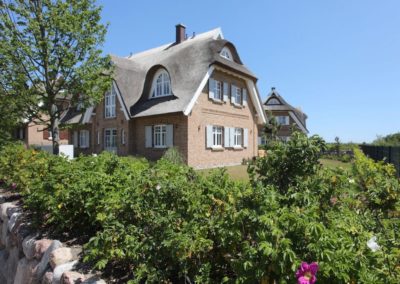 Das Ferienhaus Ruden in Lobbe auf der Insel Rügen mit Rosenhecken und Steinwall.