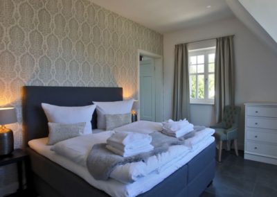 Schlafzimmer mit Doppelbett und Stuhl im Ferienhaus Ruden in Lobbe auf Rügen