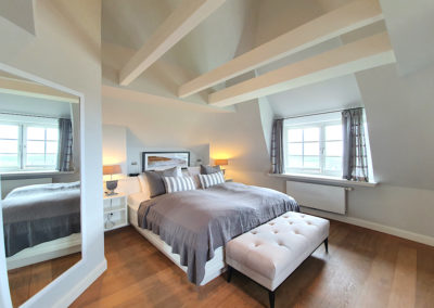 Das Hauptschlafzimmer mit offenen Dachbalken und Doppelbett im Ferienhaus Rantumhüs in Rantum auf Sylt
