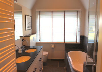Das Badezimmer mit Badewanne und Dusche im Obergeschoss 