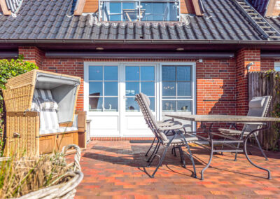 Die Terrasse mit Gartenmöbel und Strandkorb der Ferienwohnung Lüvwai in Morsum auf der Insel Sylt.